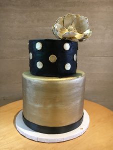 Custom two-tier black and gold fondant cake with gold flower topper, Mia's Brooklyn Bakery NYC