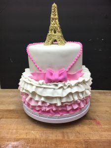 Custom two-tier Paris themed cake with Eiffel Tower topper and pink ruffle fondant decoration, Mia's Brooklyn Bakery NYC