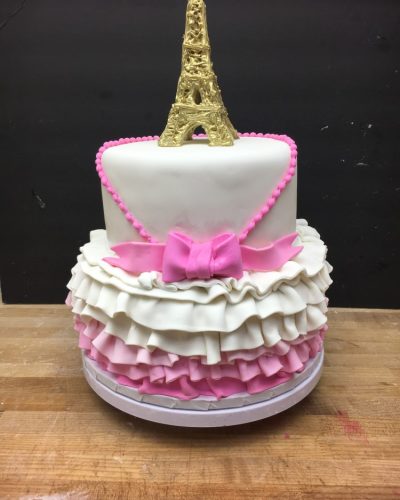 Custom two-tier Paris themed cake with Eiffel Tower topper and pink ruffle fondant decoration, Mia's Brooklyn Bakery NYC