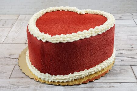 A heart-shaped red velvet cake with a deep red velvet texture and decorative white buttercream piping from Mia's Brooklyn Bakery.