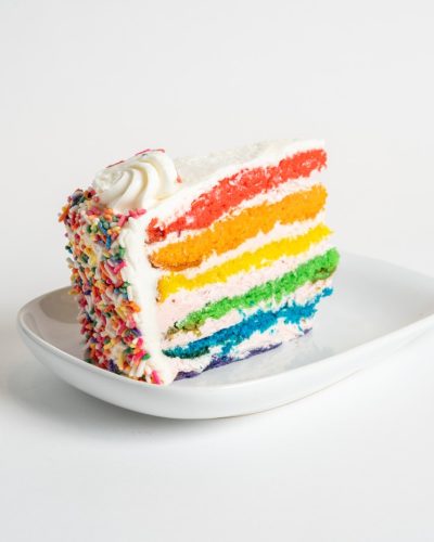 savor the classic flavor of a traditional rainbow cake slice at Mia's Bakery.