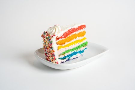 savor the classic flavor of a traditional rainbow cake slice at Mia's Bakery.